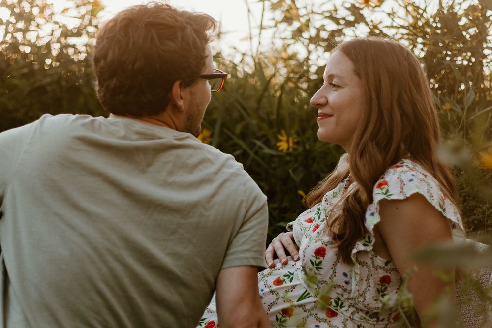 Two people share an intimate moment as golden sunlight filters through trees in a romantic outdoor setting.
