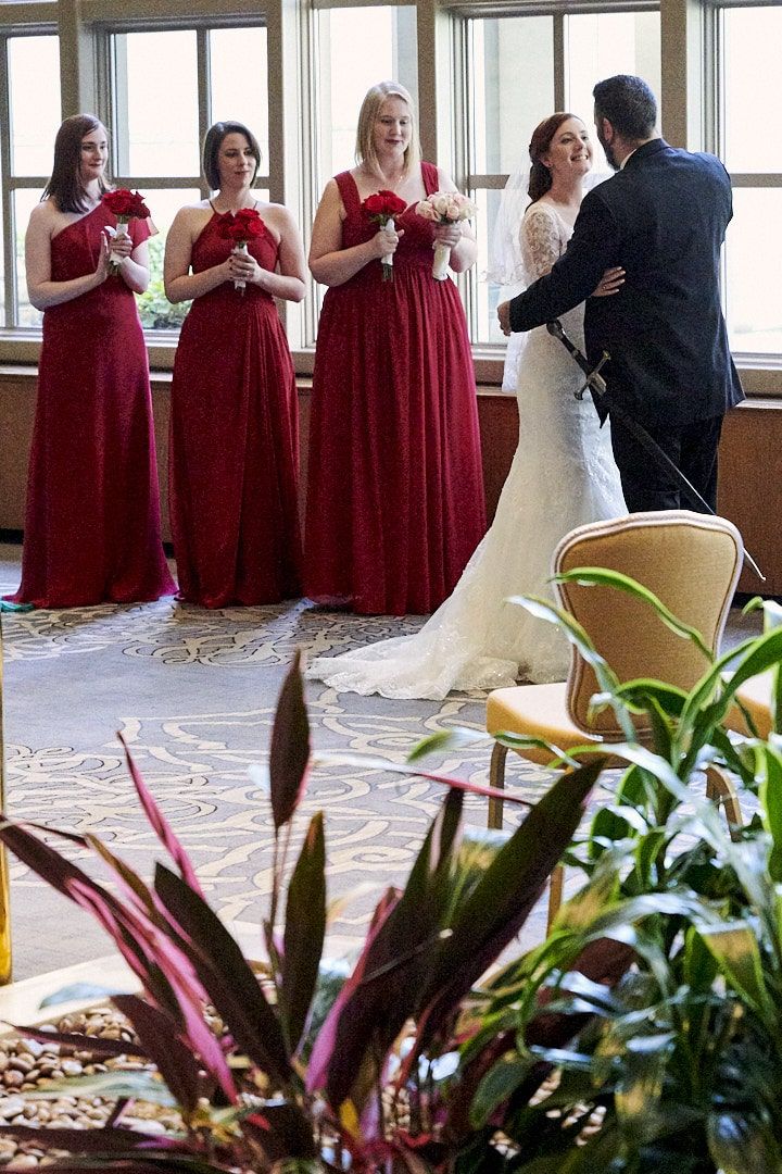Ceremony of bride and groom at Olympic Fairmount Hotel in Seattle.  Bridesmaids in red gowns standing behind bride.