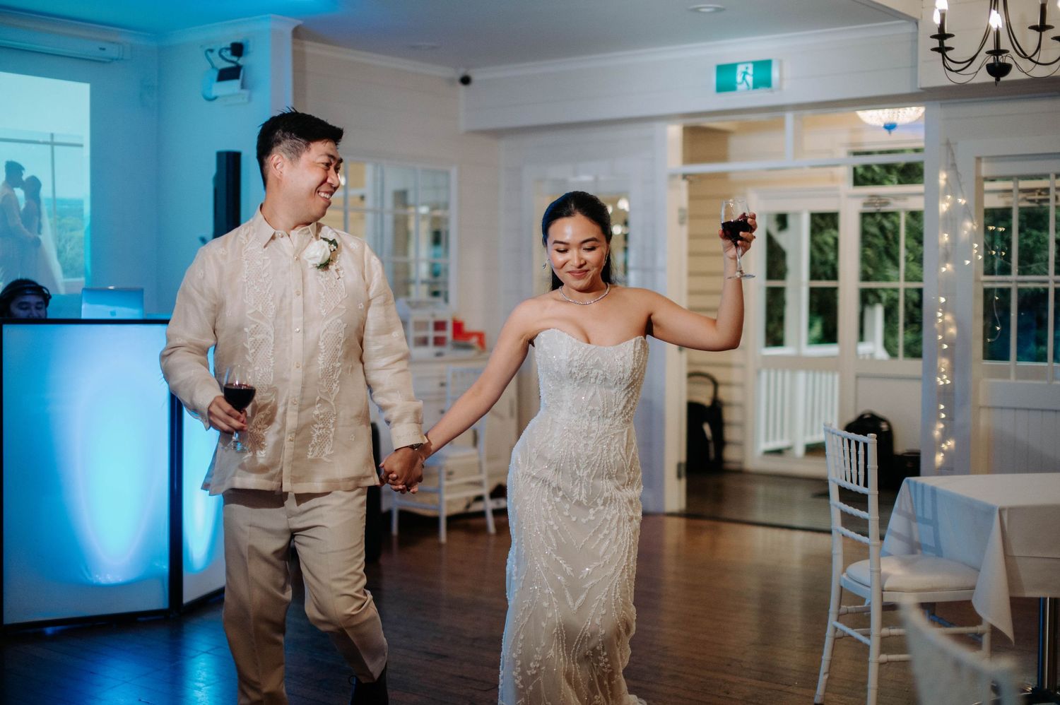 Wedding couple dancing together in a reception hall with blue ambient lighting.