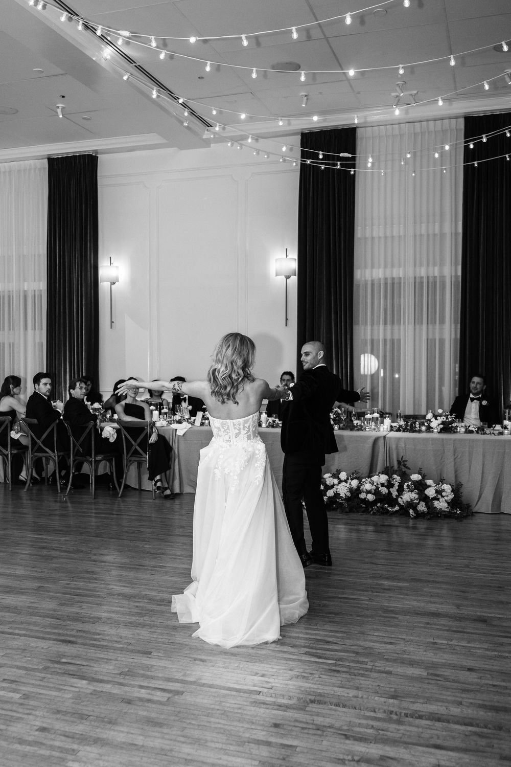 A black and white photo series showing a wedding reception venue with string lights and couples dancing on a wooden floor.