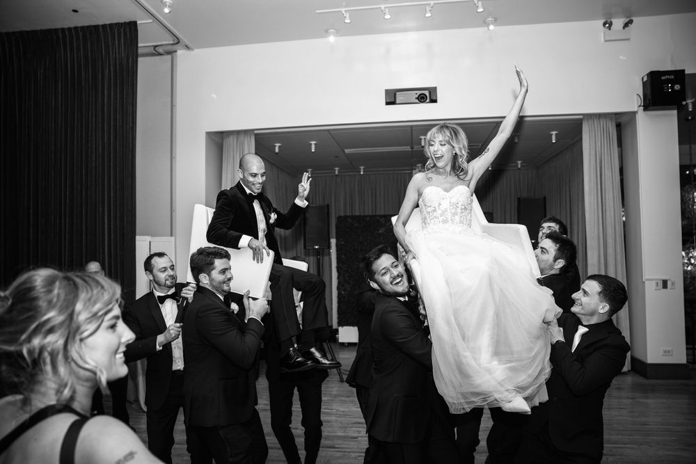 Wedding guests dancing and celebrating on a dark dance floor at an evening reception.