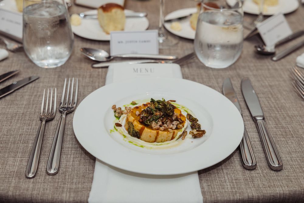 Elegant plated dishes and table settings at a formal dining event with white linens and glassware.