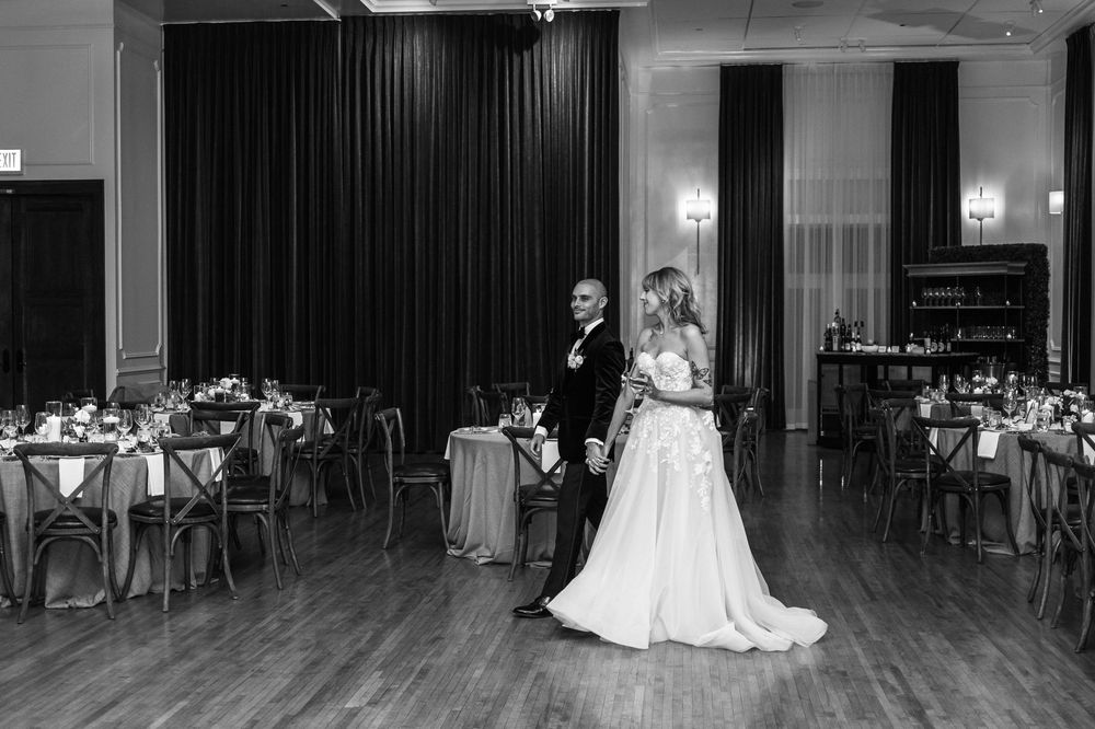 Black and white panoramic view of a wedding reception venue with tables and a dance floor.