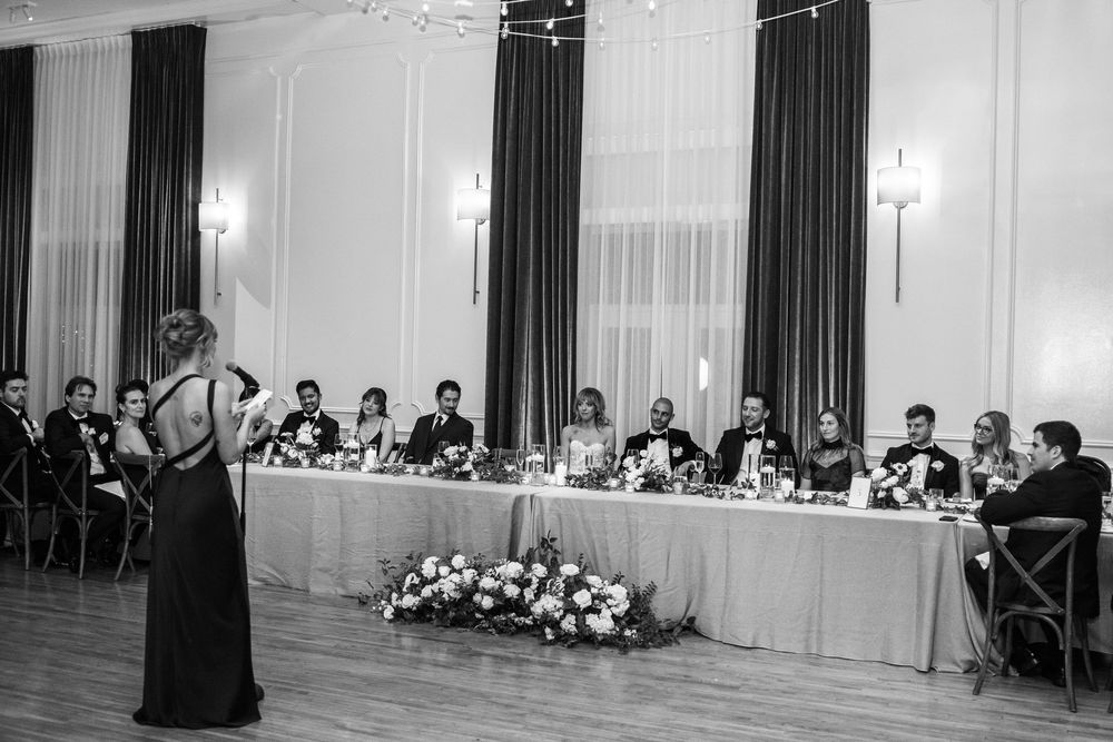 A formal banquet hall setup with long tables and dark curtains during an elegant evening event.