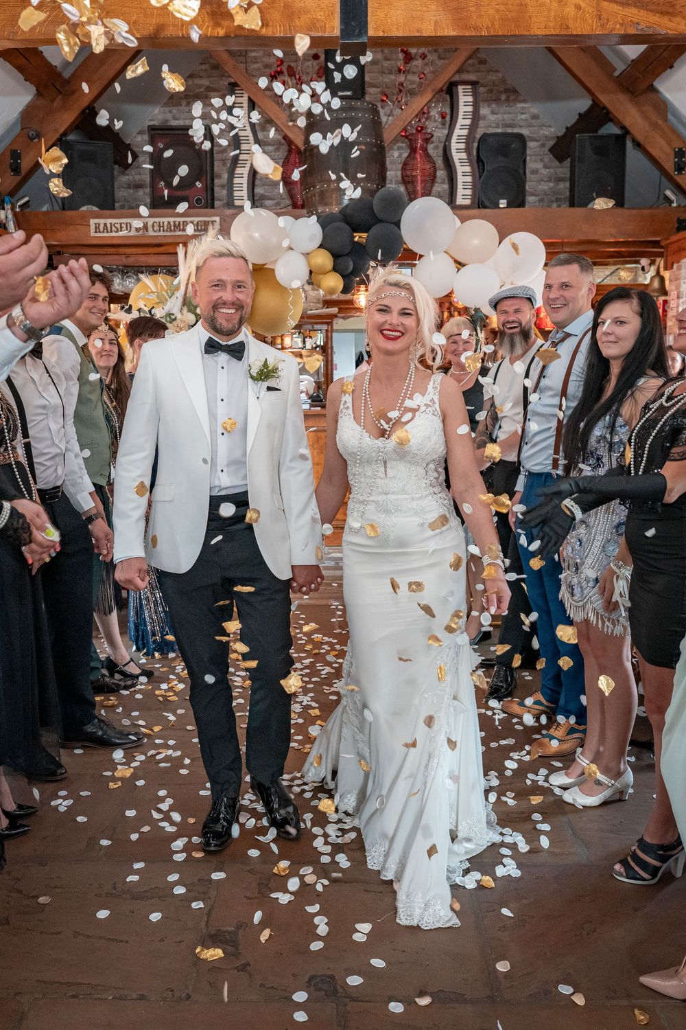 Wedding celebration with confetti being thrown in a rustic wooden venue.