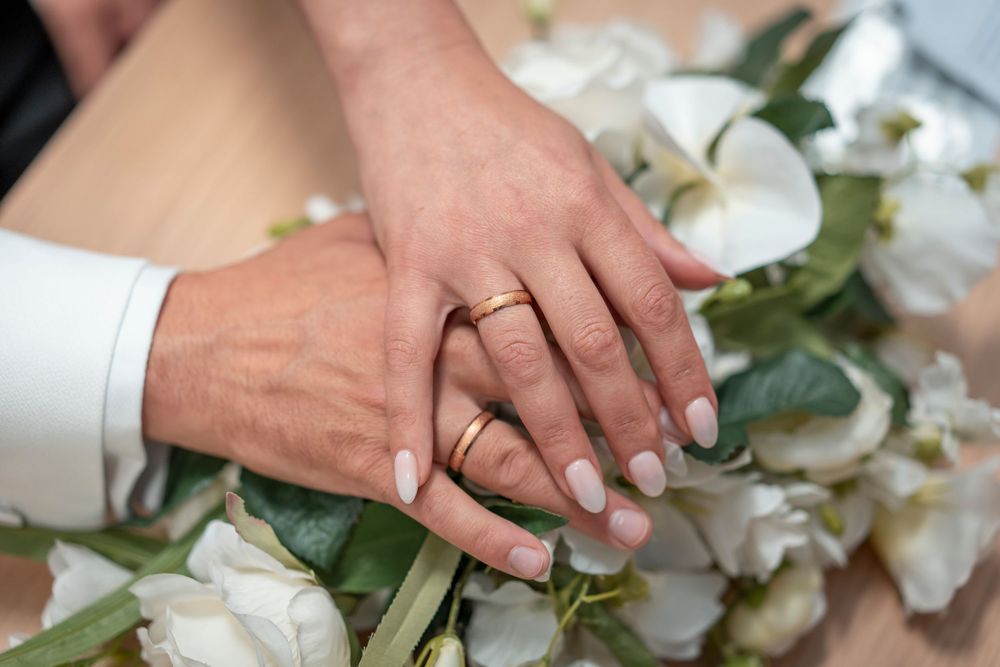 Close-up of hands holding white floral bouquets during wedding ceremony.
