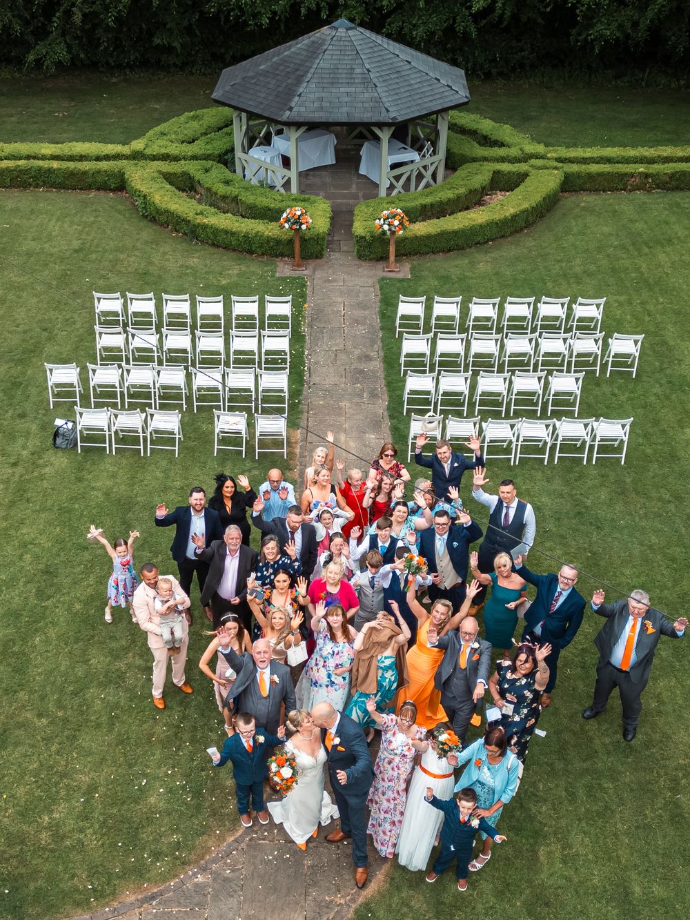 Aerial view of wedding venue with white gazebo and chairs arranged for outdoor ceremony.