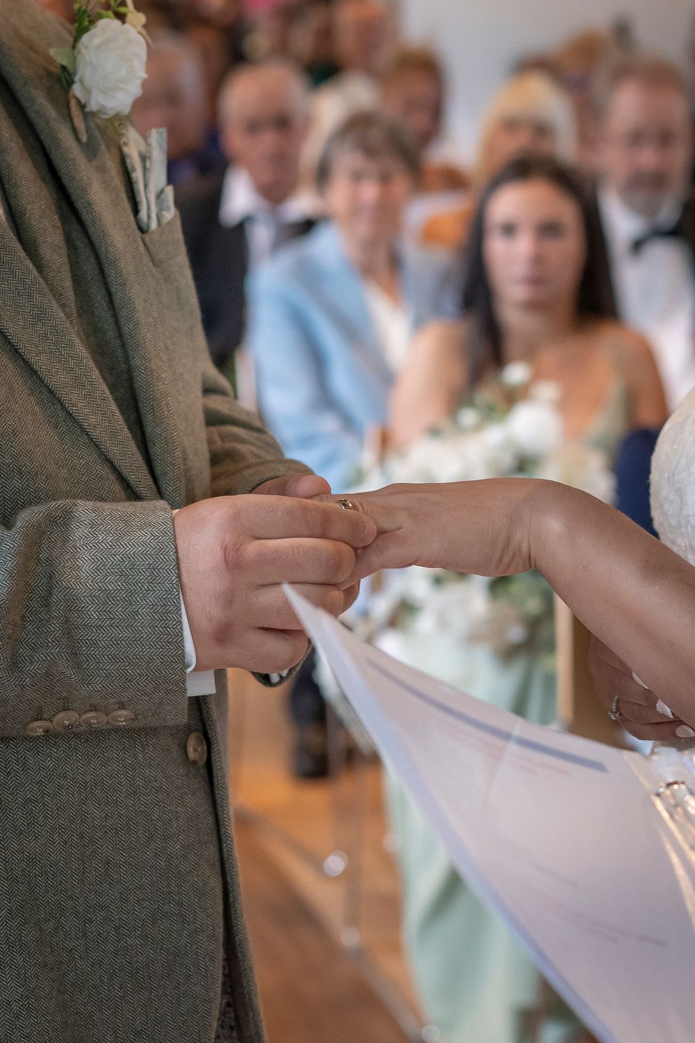 Close-up of hands exchanging rings during wedding ceremony.