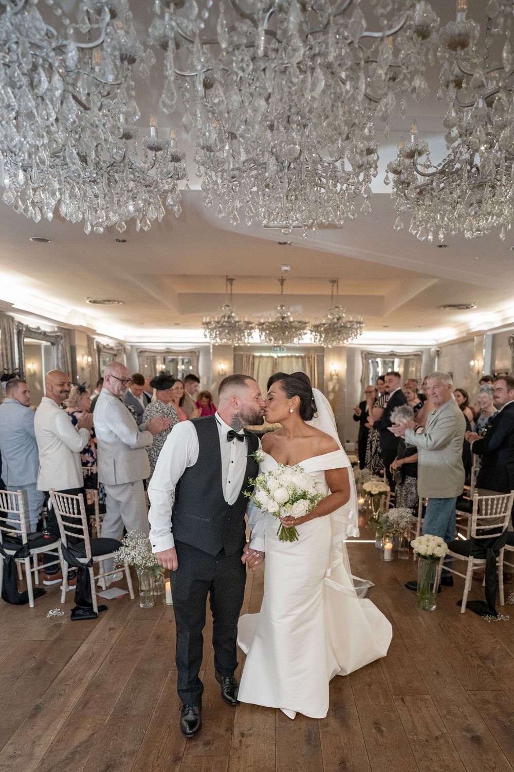 Couples dancing in an elegant ballroom under sparkling crystal chandeliers.