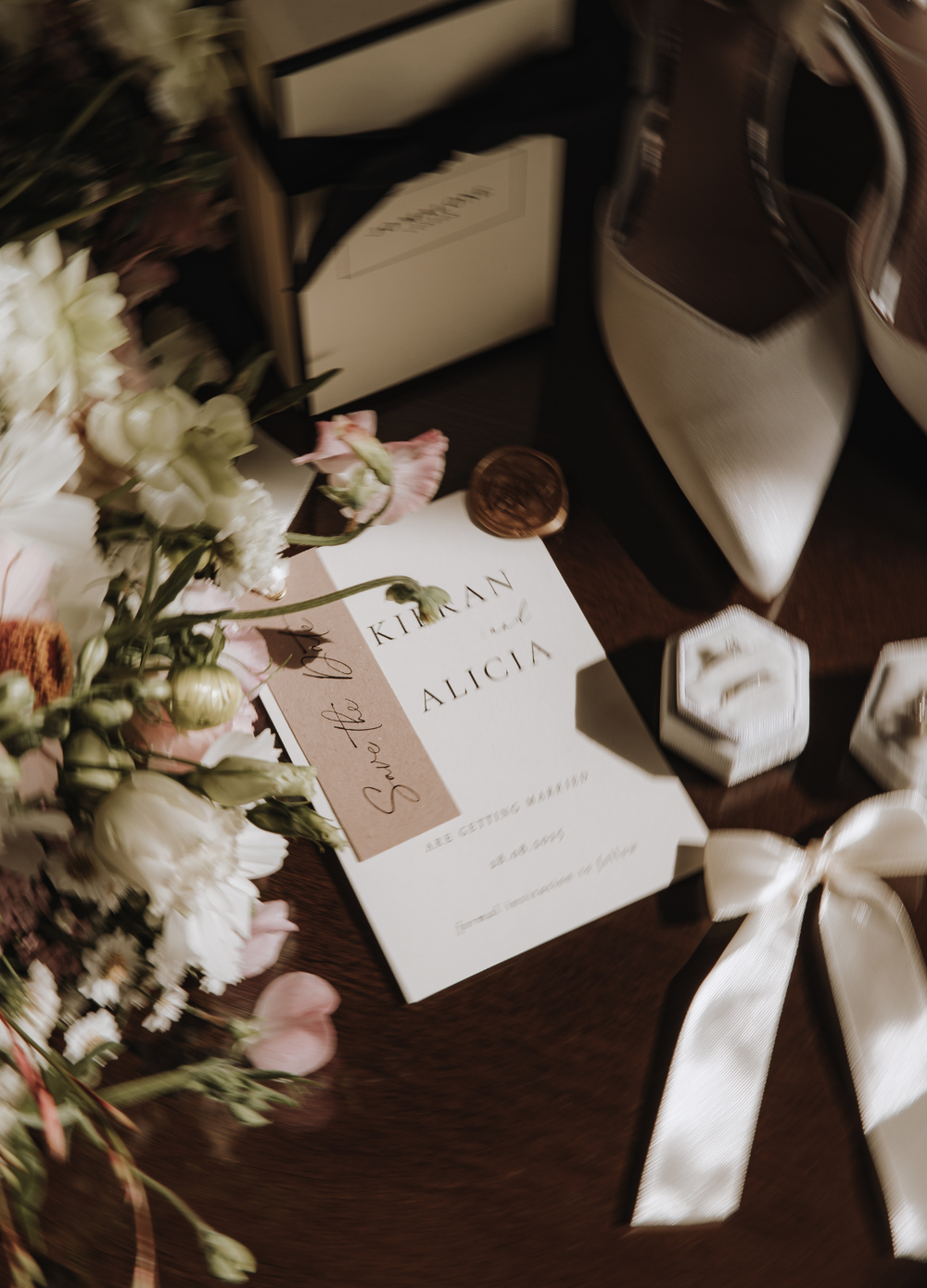 Wedding place cards and white ribbons arranged elegantly on dark wooden surface with delicate floral accents.