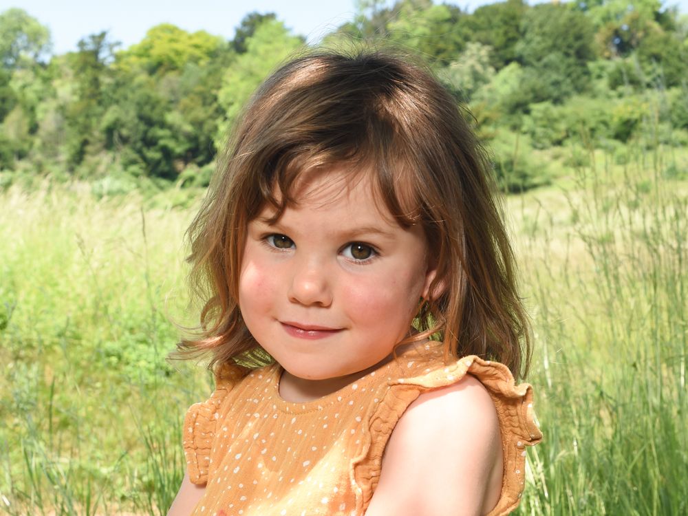 A young girl enjoys a sunny day in a field of yellow flowers in Radnage, captured by family photographer Abigail's Studio.