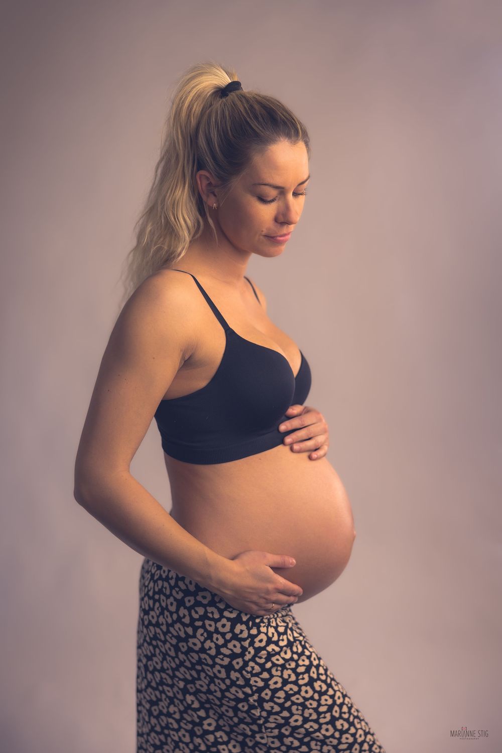 Side view progression photos showing different stages of pregnancy in black top and floral skirt against neutral background.