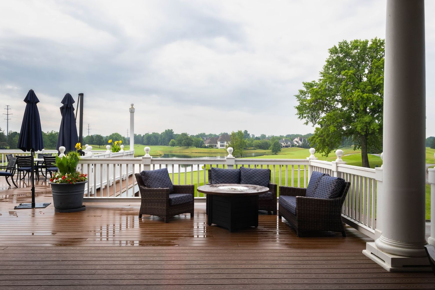 A scenic country club deck with wicker furniture overlooking a lush green golf course.