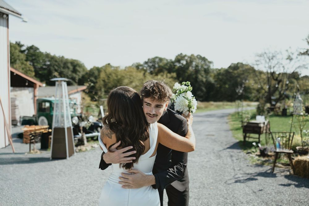 A romantic outdoor wedding celebration with couples and guests dancing and embracing in a scenic countryside setting.