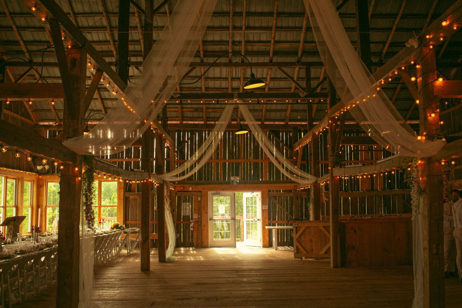Rustic wooden barn interior with warm glowing string lights creating a romantic, cozy atmosphere.