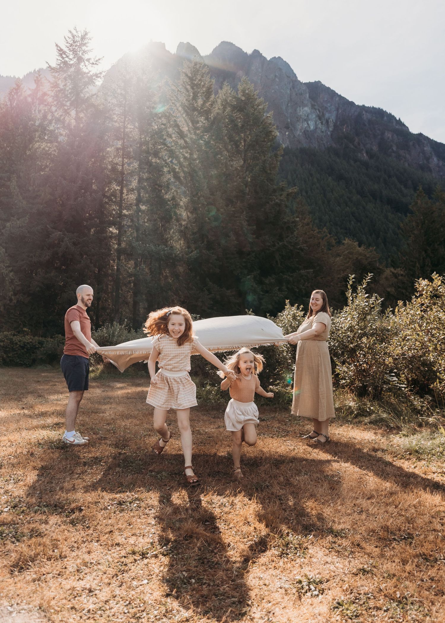 A group dances and plays together on a mountain trail during golden hour with majestic peaks in the background.