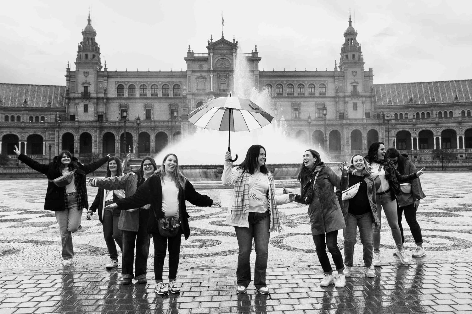 A group of people walking in silhouette across Plaza de España in Seville, Spain on a cloudy day.