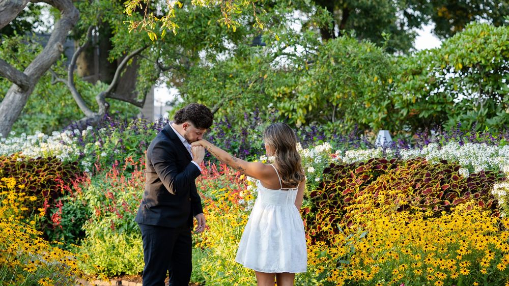 Couple sharing a romantic moment among vibrant wildflowers in a sunlit garden setting.