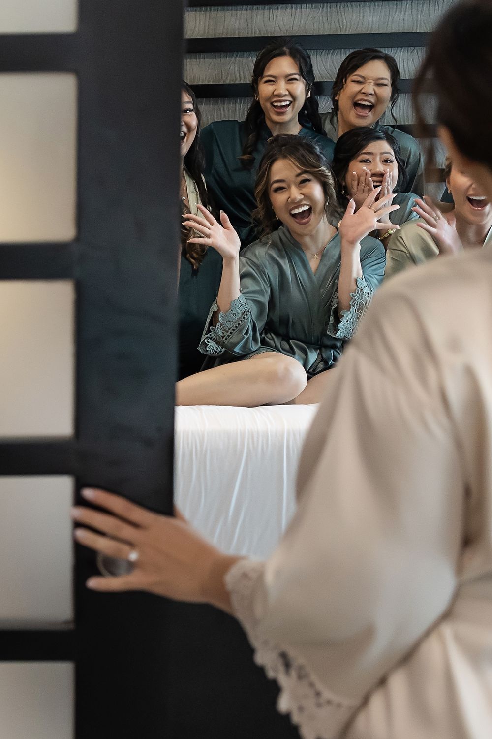 A group of friends share a joyful moment together, laughing and smiling while sitting on a white surface.