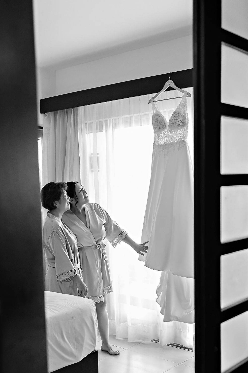 Black and white photo of people in white robes silhouetted against bright windows in a minimalist interior space.
