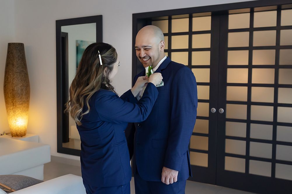 A couple in matching navy blue outfits shares an intimate moment in an elegantly lit hallway.