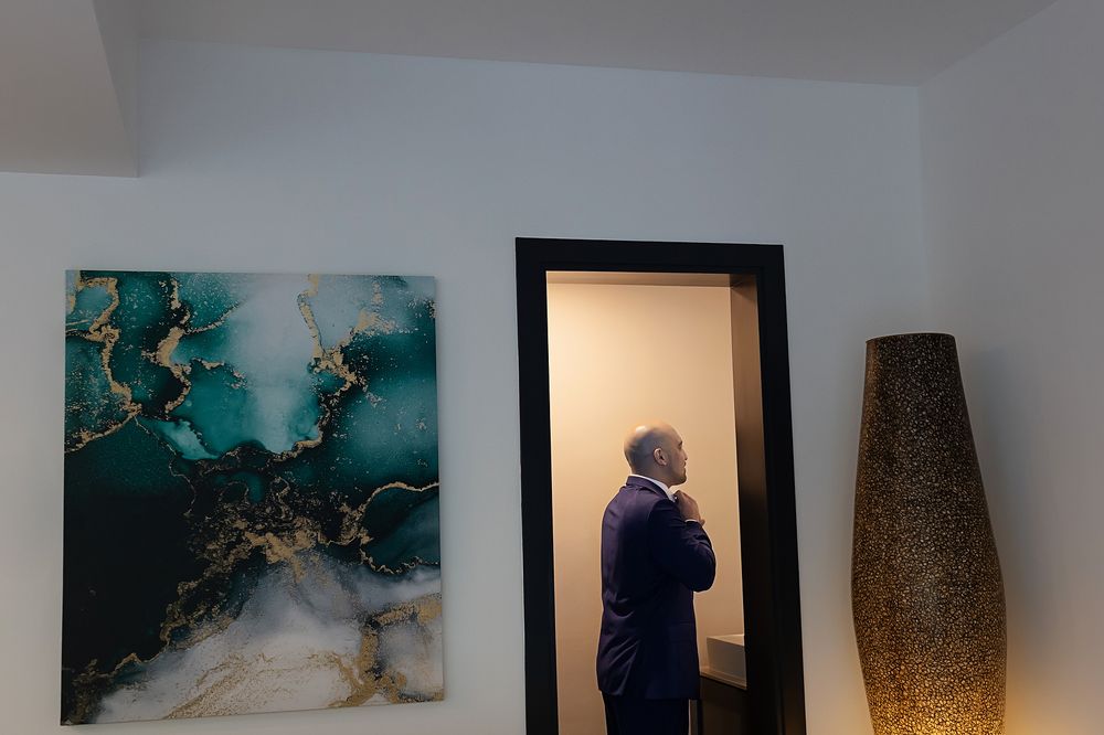 A modern interior space with abstract turquoise wall art, a black-framed mirror, and a decorative brown floor vase.