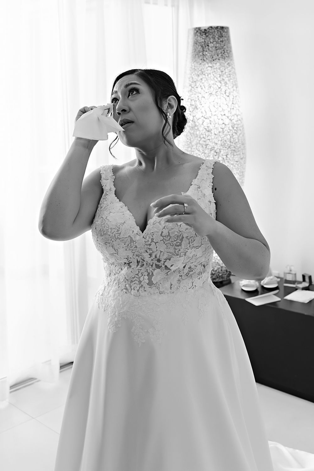 A bride in a white lace wedding dress with a sweetheart neckline and flowing skirt gets ready for her special day.