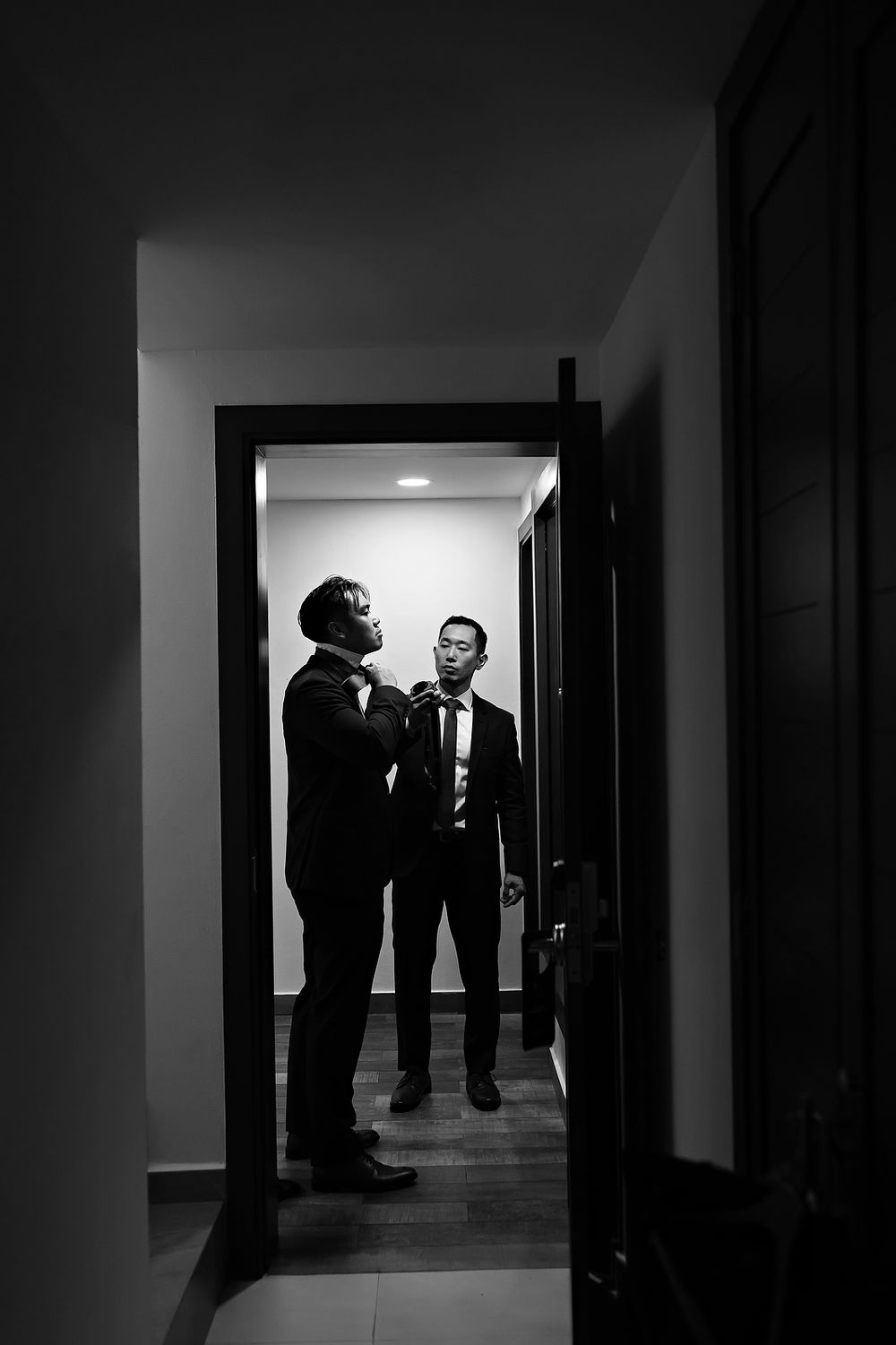 Dark silhouettes of people stand in a dimly lit hallway creating a dramatic noir-style atmosphere.