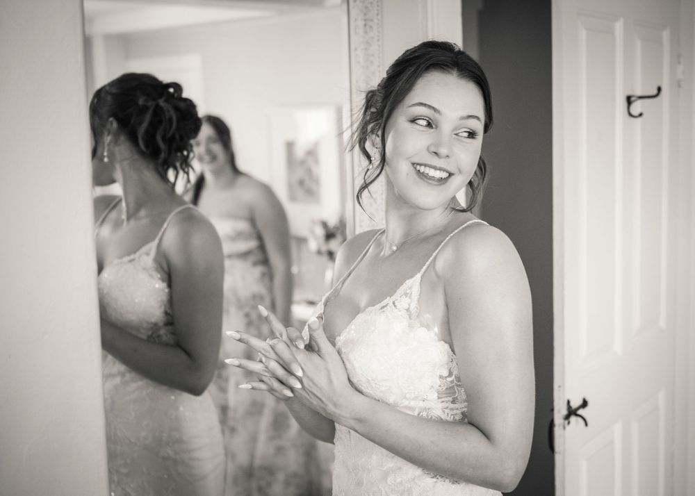 Smiling bride in wedding dress admiring her reflection in a mirror.