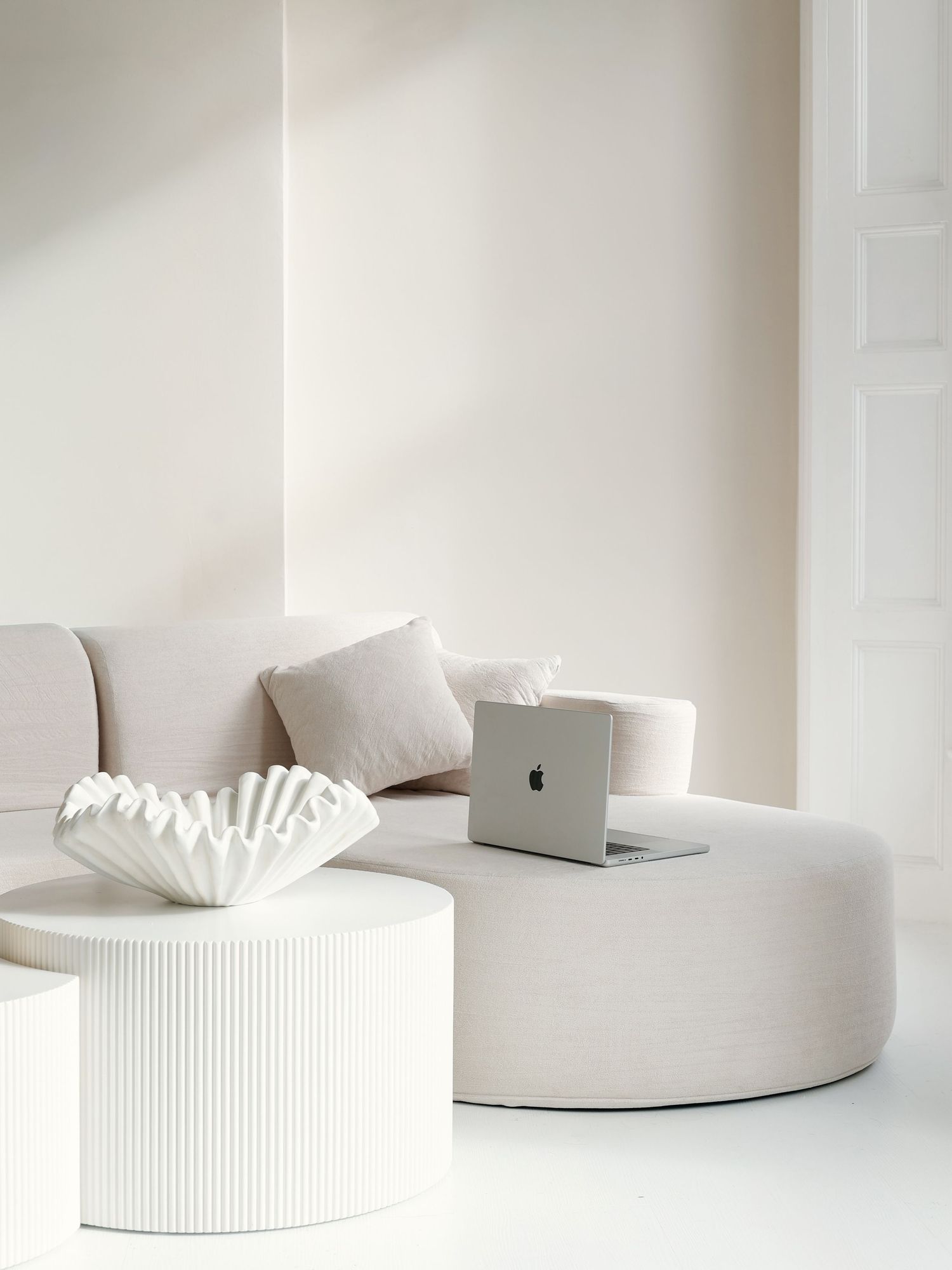 A minimalist white tissue box holder with ribbed texture sits on a clean white surface in a bright setting.