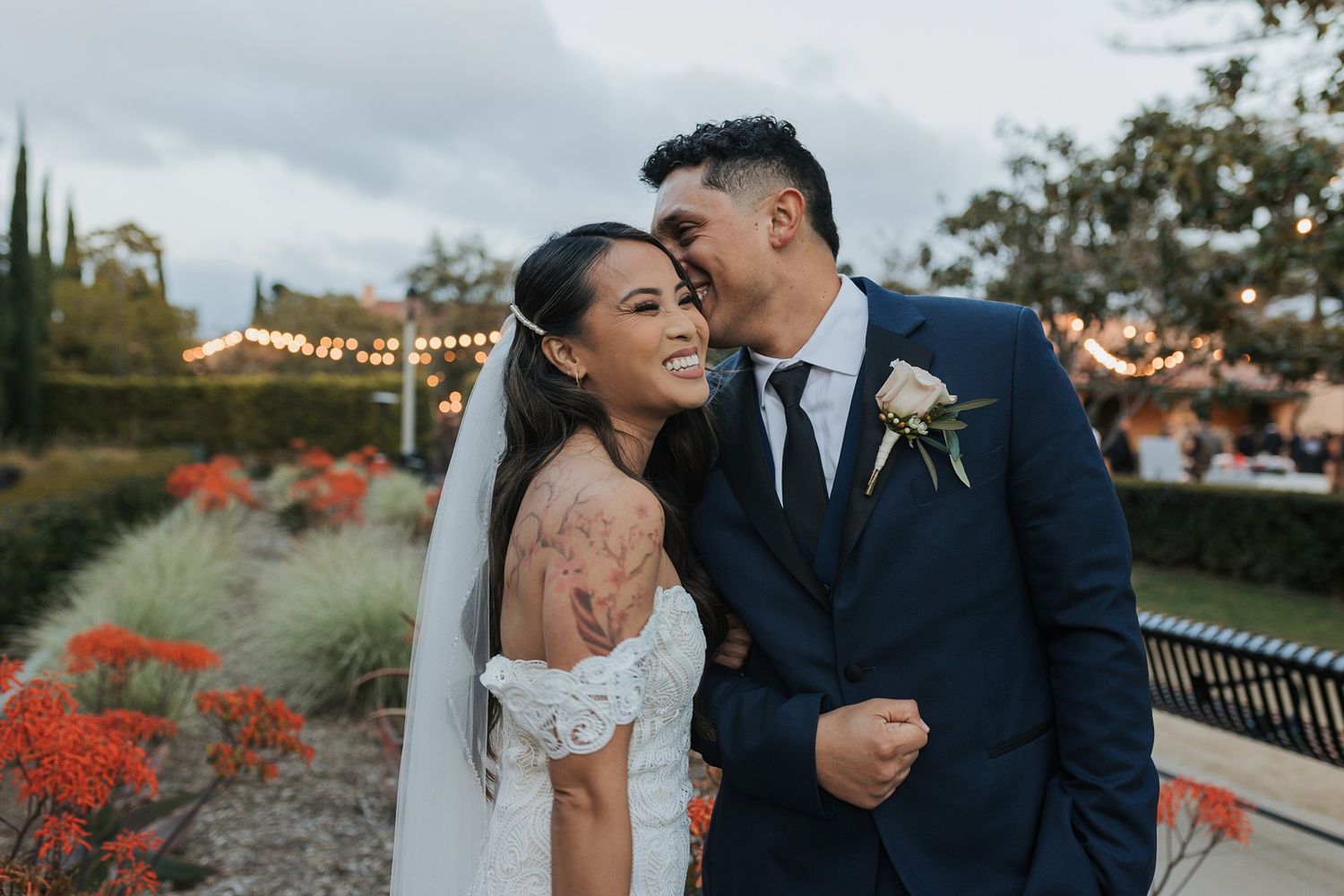 Newlywed couple shares intimate moments in various outdoor settings with red flowers and natural backdrops at Liberty Station in San Diego.