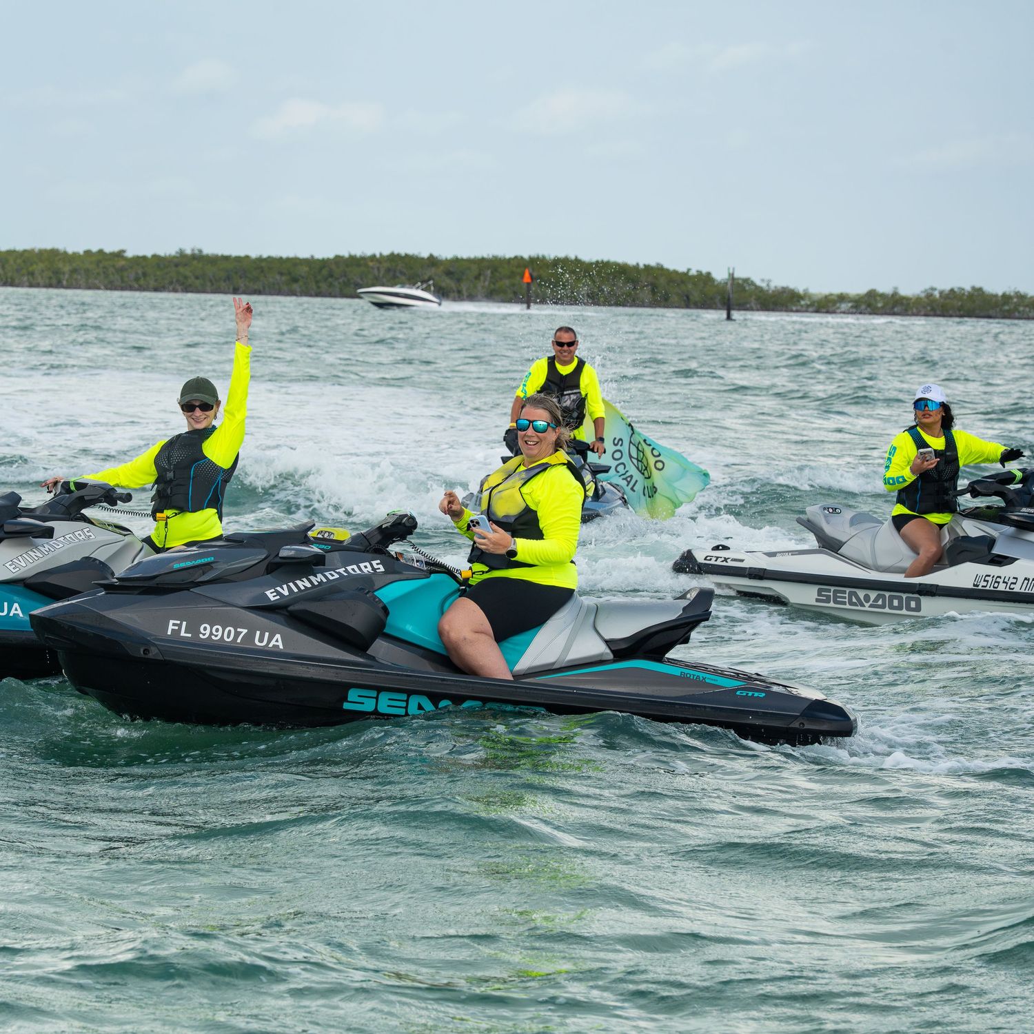 Group riding Sea-Doo jet skis in bright yellow safety vests gather on choppy waters during a guided tour.