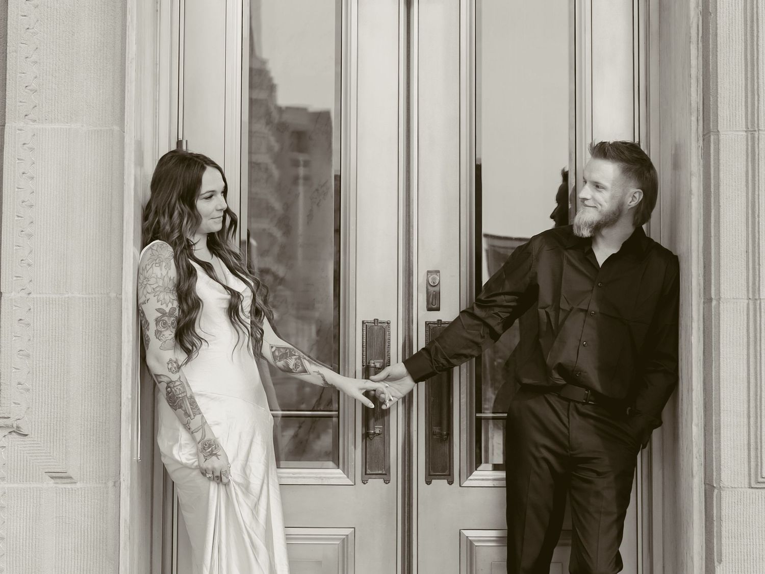 A bride and groom pose playfully in a series of four black and white photos against an elegant doorway.