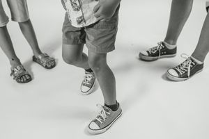 Close-up view of various shoes and feet in a line showing sneakers, sandals and other footwear styles.
