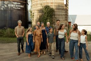 Large family group smiling together outdoors near grain silos at Calvaresi Harvestore farm on a sunny day.