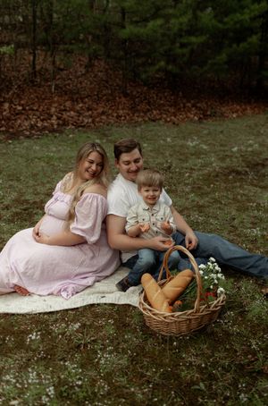 People lounging on grass with picnic basket and flowers in outdoor setting.