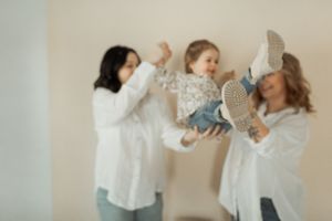 Two people in white shirts dance together joyfully in a bright room with light walls.
