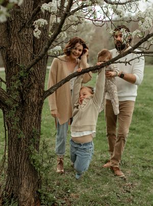 A group gathers around a rustic tree trunk in a dreamy outdoor setting with soft natural lighting.