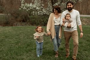 A family walking together through a spring garden with blooming cherry blossoms in the background.
