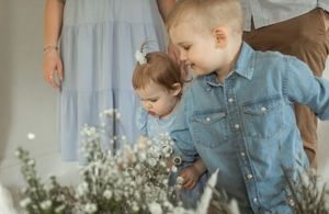 A series of candid moments captures a young child in blue denim exploring delicate white flowers on a table.