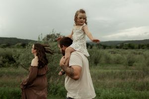 A series of maternity photos showing a pregnant woman in a white dress posing outdoors in a natural meadow setting.