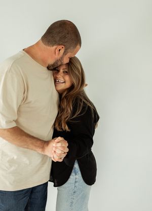 A couple in casual attire shares a playful moment against a white background in a series of candid shots.