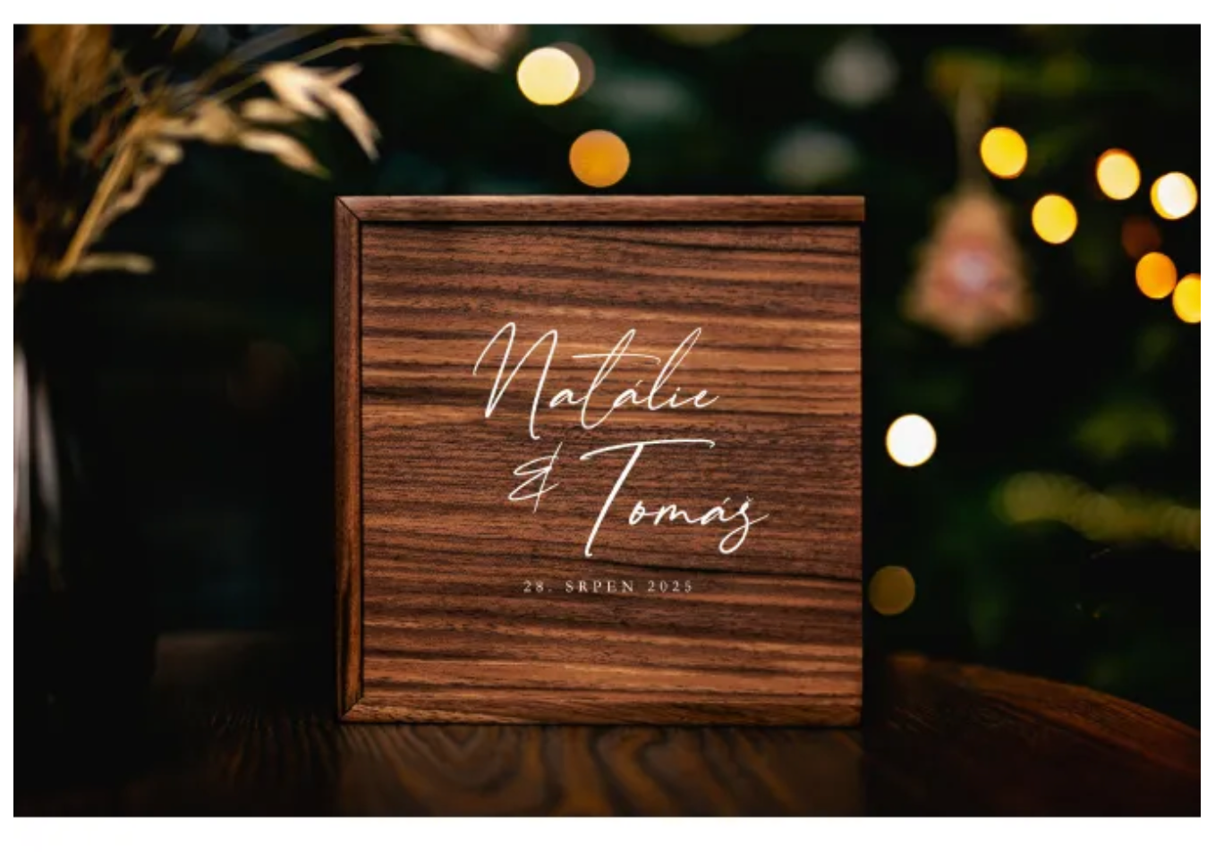 Rustic wooden wedding signs with names and dates illuminated by warm glowing lights in an evening outdoor setting.