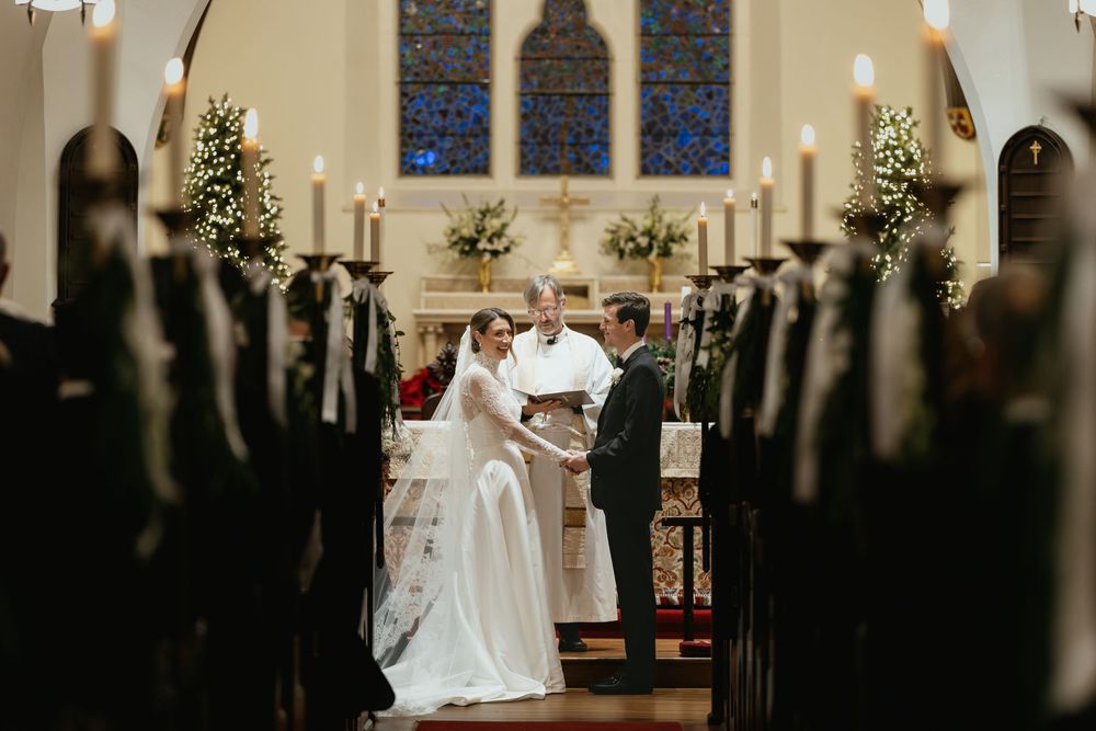A row of illuminated stained glass windows line the interior wall of a church sanctuary.