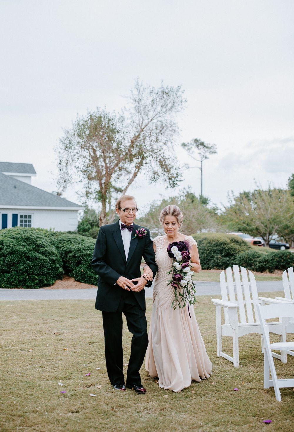 A wedding ceremony setup outdoors with white chairs arranged in rows on a grassy lawn.