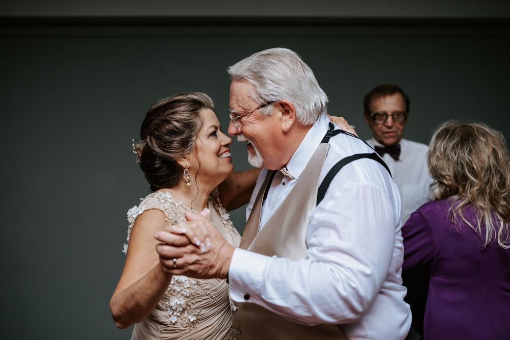 A couple shares a tender dance moment during their wedding reception in a dimly lit venue.