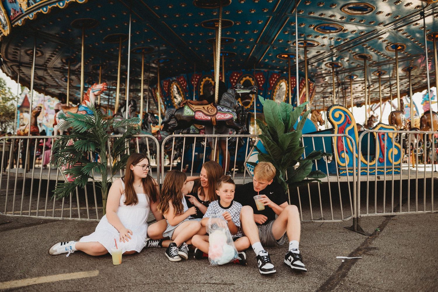 Friends sitting together and laughing on a carnival ride during a fun summer evening at an amusement park.