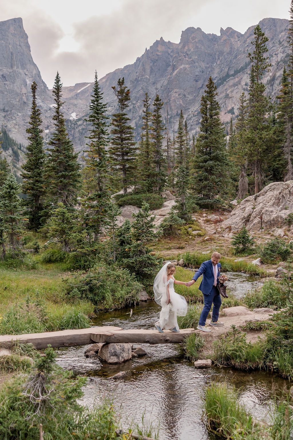 Bride and Groom cross stream near Dream Lake at Rocky Mountain National park.