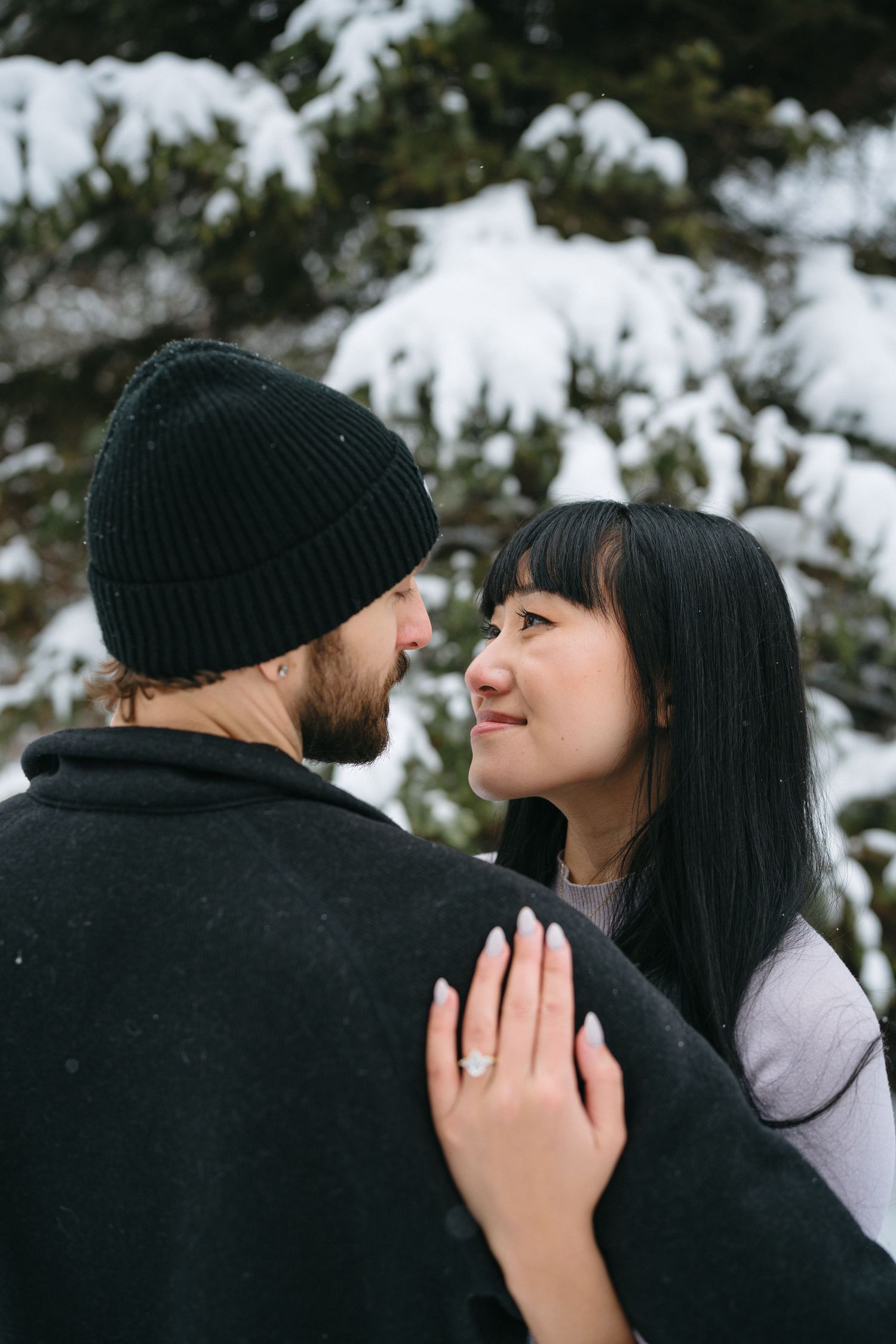 A romantic couple shares tender moments in a snowy winter setting while wearing cozy winter attire.