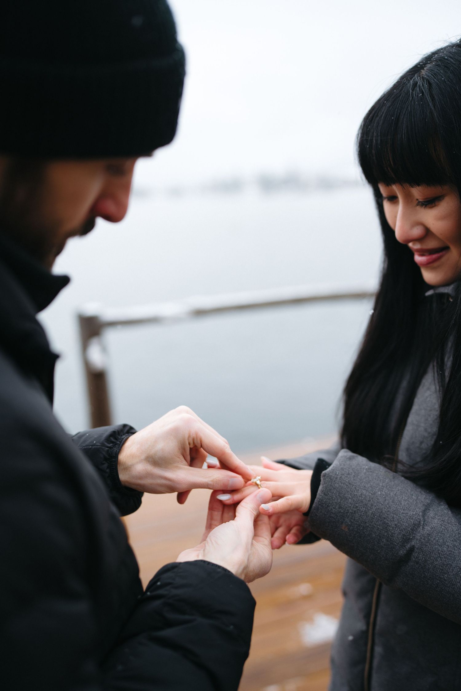 Two people's hands exchanging a ring in an intimate moment outdoors.